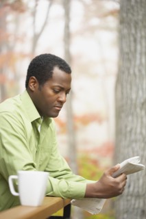 African man reading newspaper outdoors