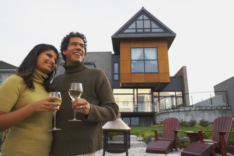 Couple holding wine in front of house