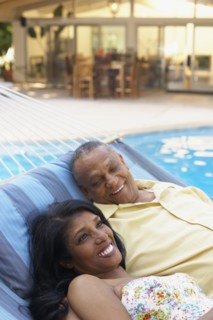 Multi-ethnic couple laying in hammock at poolside