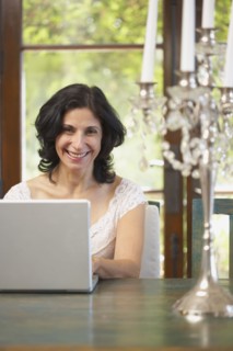 Confident Middle Eastern woman typing on laptop in dining room