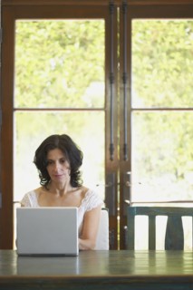 Confident Middle Eastern woman typing on laptop in dining room