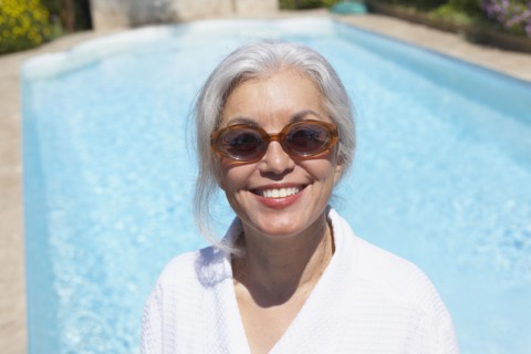 Woman at poolside in bathrobe and sunglasses