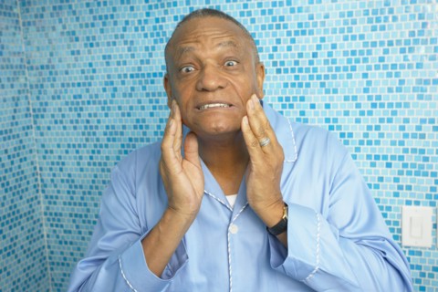 African man checking is wrinkles in bathroom