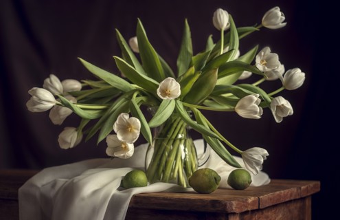 White flowers in vase with limes and blanket