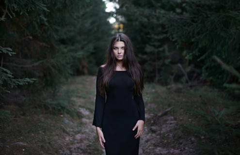 Caucasian woman wearing black dress in forest