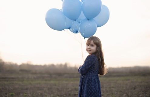 Caucasian girl holding blue helium balloons