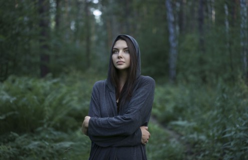 Cold Caucasian woman standing in forest