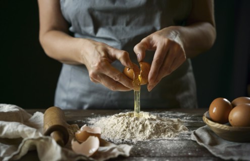 Caucasian woman cracking egg over flour