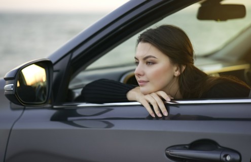 Pensive Caucasian woman leaning in car window