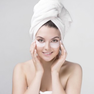 Caucasian woman applying makeup to cheeks