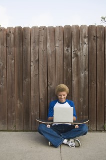 Mixed race boy typing on laptop outdoors