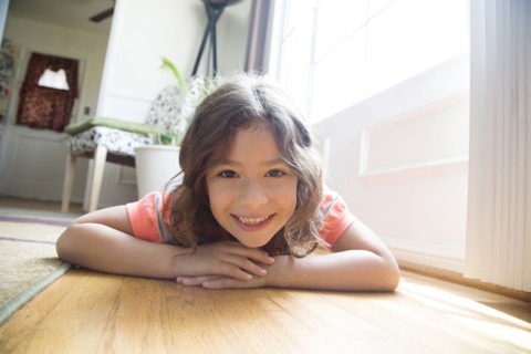 Smiling Hispanic girl laying on floor