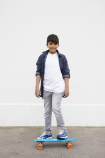 Asian boy standing on skateboard