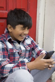 Asian boy using cell phone at door