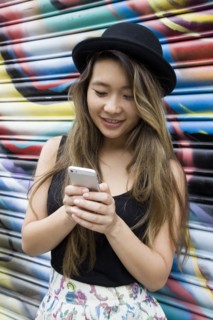 Asian woman using cell phone near graffiti wall