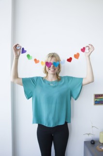 Caucasian woman covering eyes with string of paper hearts
