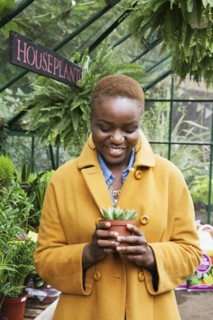 Portrait of smiling Black woman holding potted plant