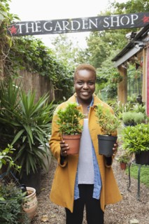 Portrait of smiling Black woman holding potted plants