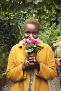 Portrait of smiling Black woman smelling flowers
