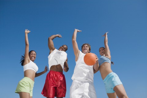 Multi-ethnic friends jumping with volleyball
