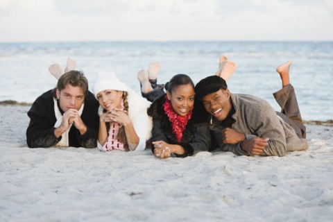 Multi-ethnic couples laying on beach