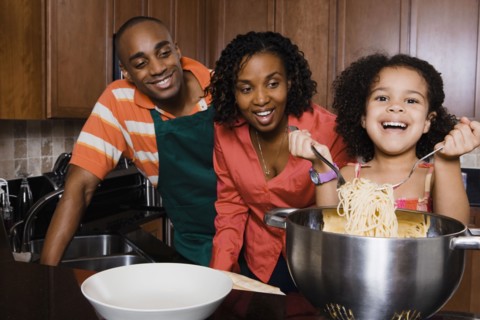 African parents watching daughter serve spaghetti