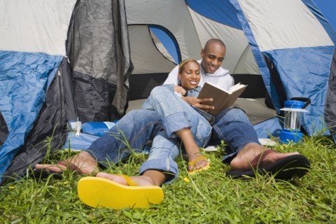 African couple reading at campsite