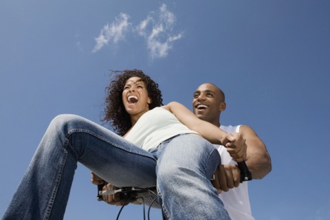 Multi-ethnic couple sitting on bicycle