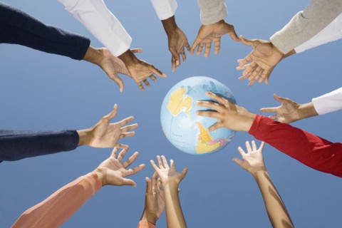 Multi-ethnic hands reaching for globe ball