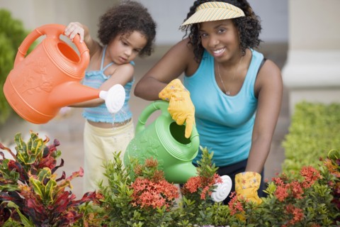 African mother and daughter watering flowers