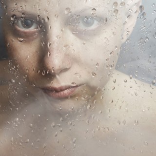 Caucasian woman peering through wet glass
