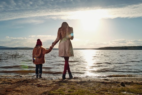 Caucasian mother and daughter standing on beach