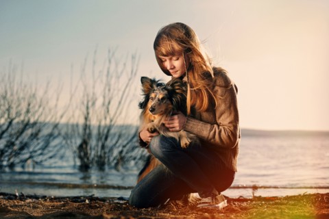 Caucasian girl petting dog near remote lake