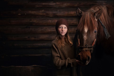 Caucasian girl standing with horse in barn