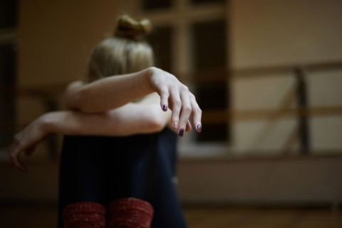 Fatigued Caucasian dancer sitting on studio floor
