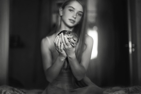 Caucasian girl holding pet chinchilla on bed