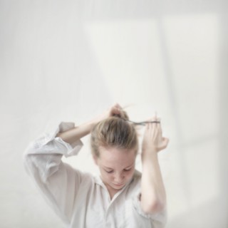 Caucasian teenage girl tying her hair into bun