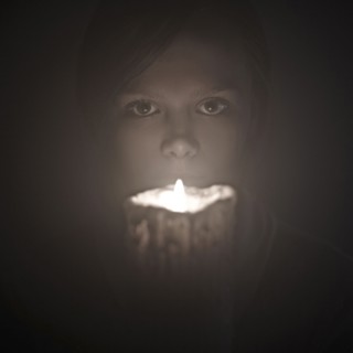Caucasian woman holding candle near face