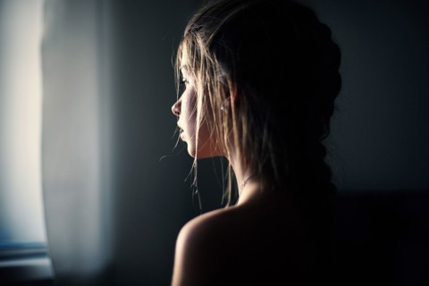 Caucasian teenage girl looking out window