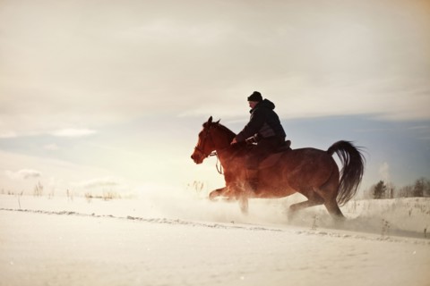 Caucasian man riding horse in snowy landscape