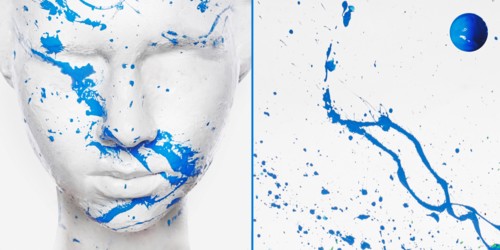 Caucasian woman in white makeup splashed with blue paint
