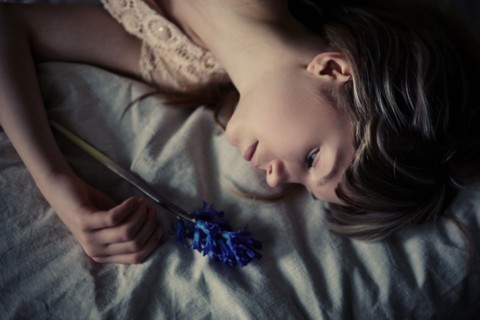 Caucasian teenage girl holding flower on bed