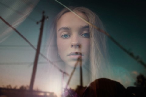 Double exposure of Caucasian girl in blue sky