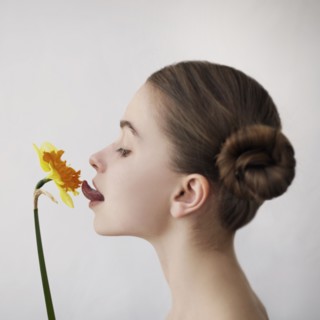 Caucasian girl licking yellow flower