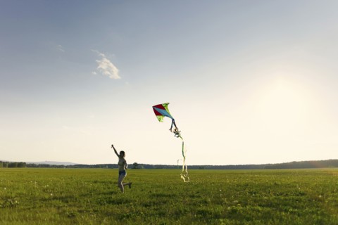 Caucasian girl running in field flying kite