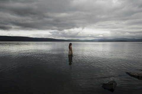 Caucasian girl wading in lake