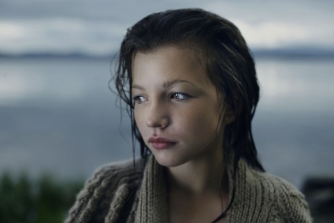 Pensive Caucasian girl with wet hair at lake