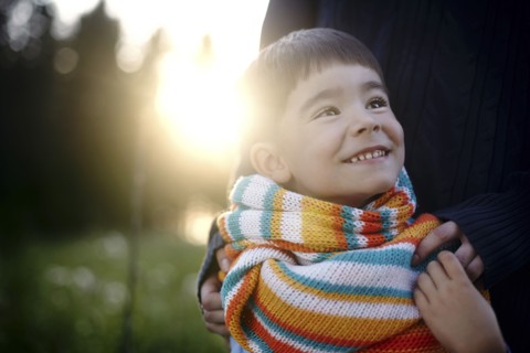 Caucasian woman holding shoulders of boy wearing multicolor scarf