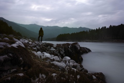 Caucasian girl standing on rocks over foggy river