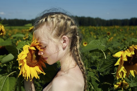 Caucasian girl smelling sunflower